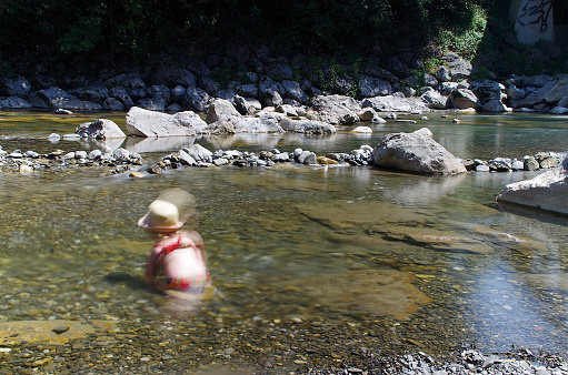 Little girl playing alone in the water, long pose effect and blurred child