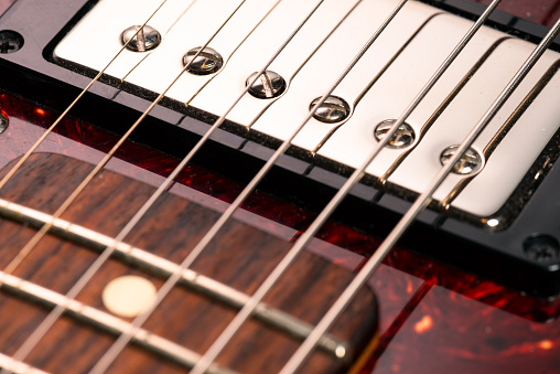 Close-up showing a humbucker neck pickup under the strings on an electric guitar.