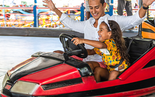 Father and daughter have fun, driving bumper car in amusement park