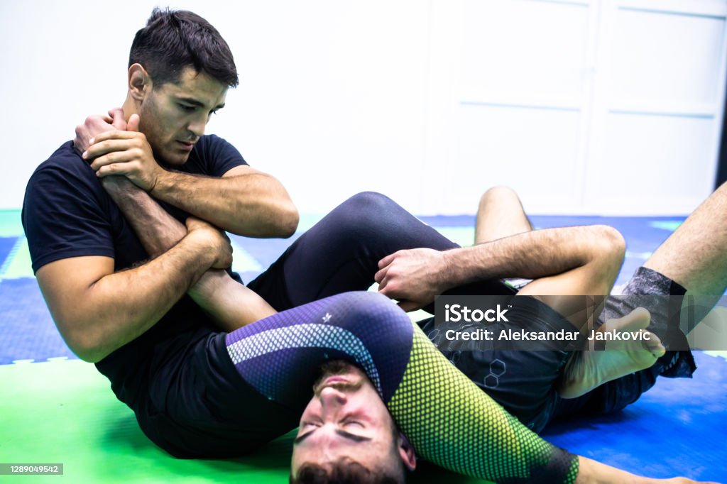 Fighters at BJJ practice Brazilian jiu-jitsu fighters are fighting in a gym Combat Sport Stock Photo