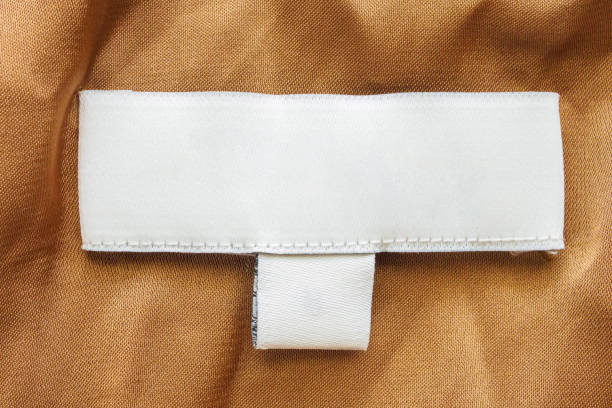 istock Blank white laundry care clothes label on brown fabric texture background 1289049922
