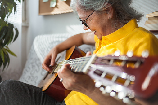 Close up of Senior woman playing guitar ay home