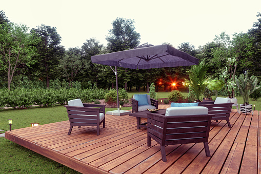 Patio con asientos de madera, mesa de centro y sombrilla en el jardín con fondo de puesta de sol. photo