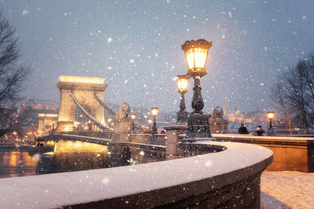 beleuchtete szechenyi kettenbrücke von budapest in einer verschneiten winterlandschaft in der dämmerung - chain bridge budapest night bridge stock-fotos und bilder