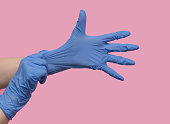 Hands put on rubber medical gloves on a pink background. Virus safety.