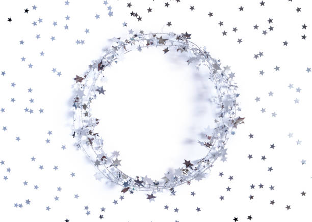 Christmas layout. A round frame made of glittering garlands is decorated with confetti in the shape of stars. White background. New Year, winter concept. Greeting card. Flat lay, copy space. stock photo