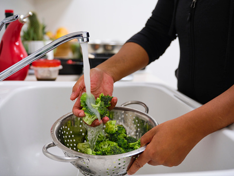 A woman prepares a healthy meal in her kitchen, using a scale to portion the ingredients.