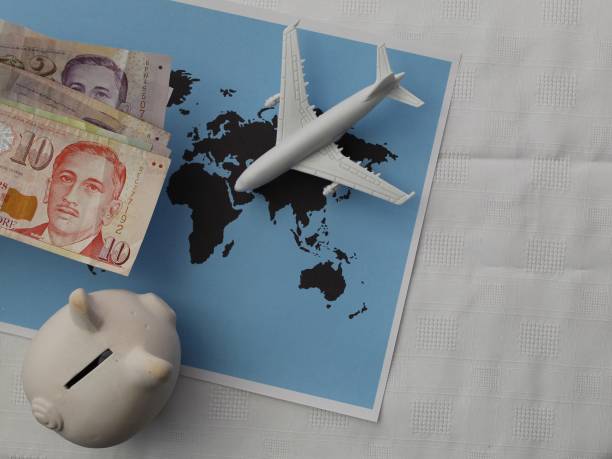 travel planning with Singapore money Singaporean money, figure of an airplane and piggy bank on a sheet with a world map singapore cash stock pictures, royalty-free photos & images