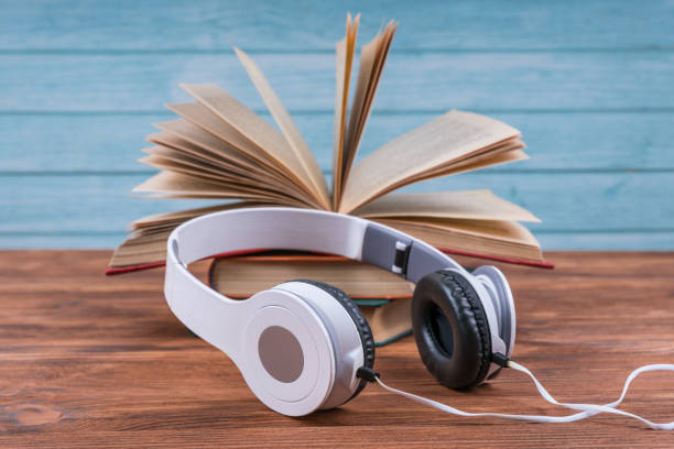 istock Beautiful open book and white headphones. Concept Audiobook 1289064984