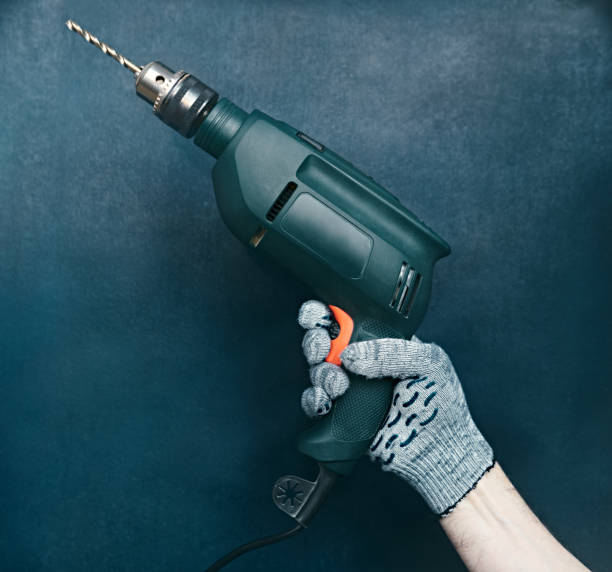 istock Green drill in the hand of the builder on a blue background, shallow depth of sharpness, concept of repair and construction 1289065093