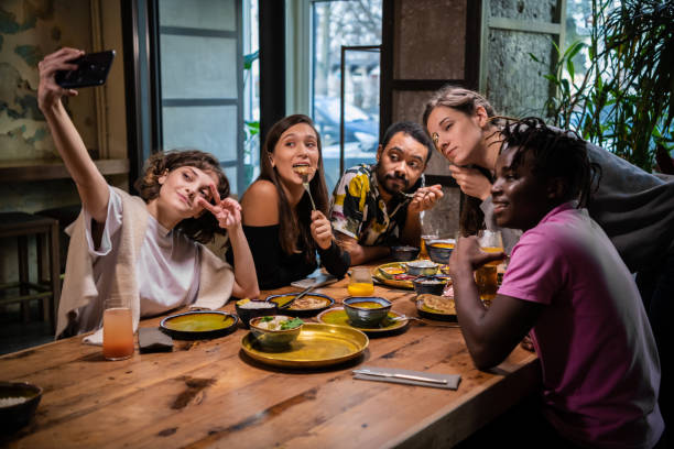 istock Five young friends sitting at the table in a cafe, taking selfie 1289067769