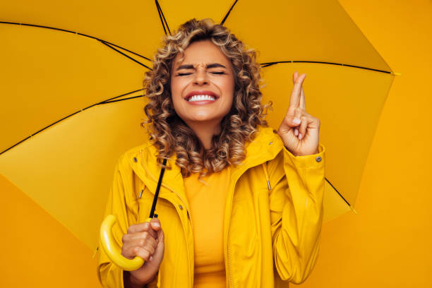 Girl holding yellow umbrella and and showing hope signGirl with yellow umbrella