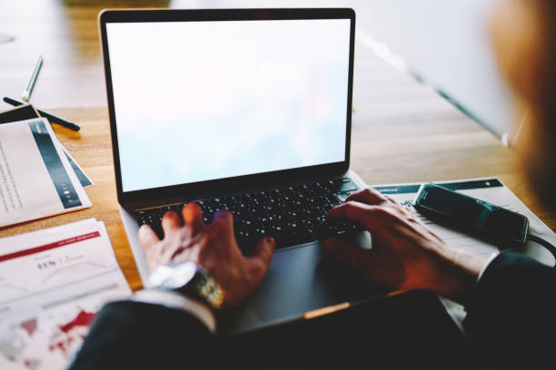 istock Cropped male entrepreneur using mockup laptop for analyzing online investment connected to office internet, experienced businessman browsing information on blank netbook with copy space area 1289070168