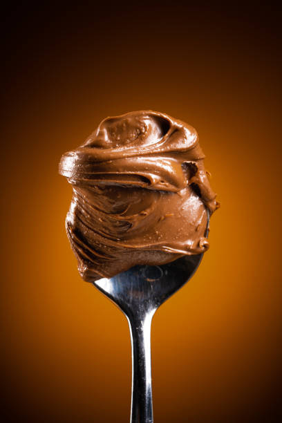 Cream chocolate in spoon on dark background