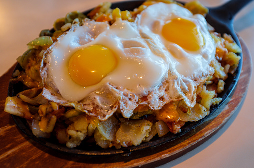 Two sunny side up eggs with home fries served on skillet