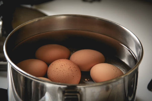 난로에 작은 냄비에 끓는 갈색 계란 - steam saucepan fire cooking 뉴스 사진 이미지