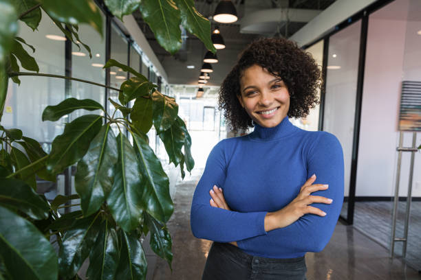 Green Office Pretty biracial woman, standing in an office surrounded by plants turtleneck photos stock pictures, royalty-free photos & images