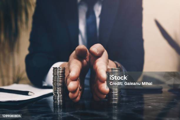Businessman Separates Stack Coins Concept Of Saving And Investing Property Division Divorce And Legal Services Stock Photo - Download Image Now
