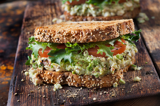 Toasted Avocado and Egg Salad Sandwich with Crispy Bacon, Lettuce and Tomato on Whole Grain Bread