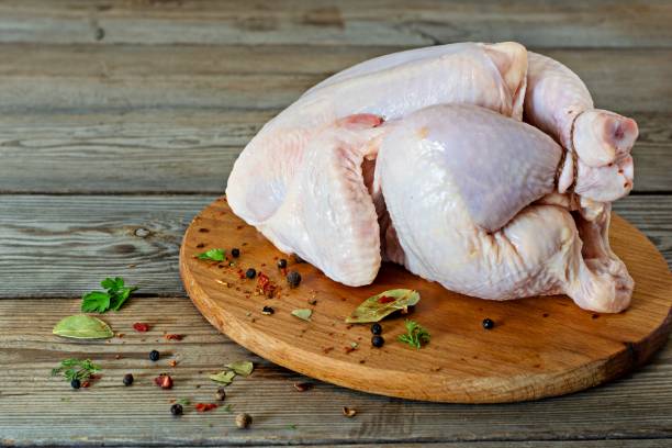 istock Raw chicken carcass ready for cooking on a cutting board on wooden background. 1289092493