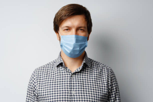istock Man wearing hygienic mask against grey background 1289092654