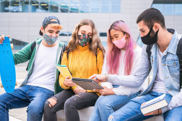 многорасовые друзья-подростки носить маску, сидя на скамейке tha вне школы - новая нормальная концепция образа жизни с молодыми студентами ш� - tha стоковые фото и изображения