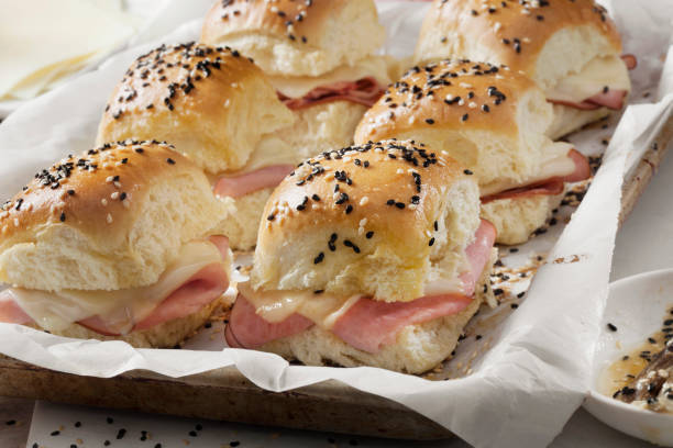 baked ham and swiss sliders on white tray buns - sesame bun american culture cheddar imagens e fotografias de stock