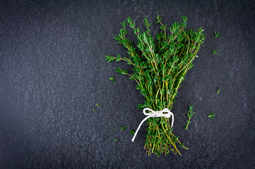 Fresh Thyme on a slate background tied with rustic string, shot on a grey slate background. Overhead view with copy space.