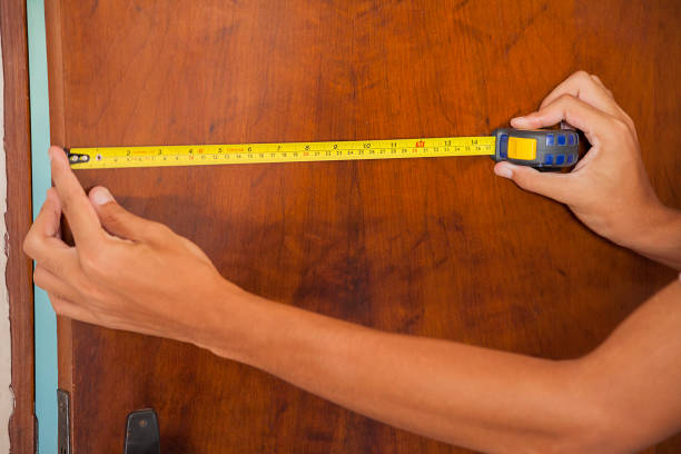 홈 도어 측정. 측정 테이프를 사용하여 남자에 의해 측정되는 나무 문. 사진과 함께 손과 팔이 등장하며, 천연 나무 문도 함께 등장합니다. - carpenter home addition manual worker construction 뉴스 사진 이미지