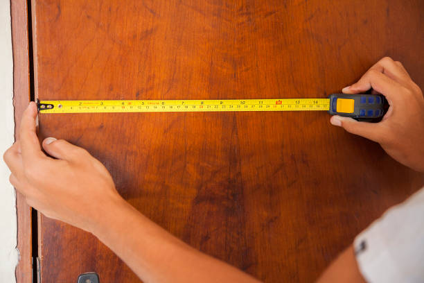 홈 도어 측정. 측정 테이프를 사용하여 남자에 의해 측정되는 나무 문. 사진과 함께 손과 팔이 등장하며, 천연 나무 문도 함께 등장합니다. - carpenter home addition manual worker construction 뉴스 사진 이미지