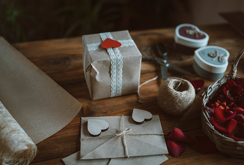 Close up of wrapping valentine gifts on wooden table.