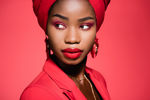 african american young woman in stylish outfit and turban isolated on red