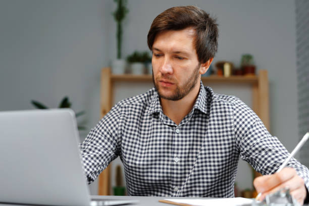 istock Young man working on laptop at his working table 1289120448