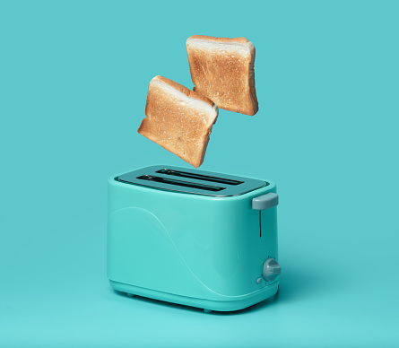 Bread popping up of toaster on mint green background