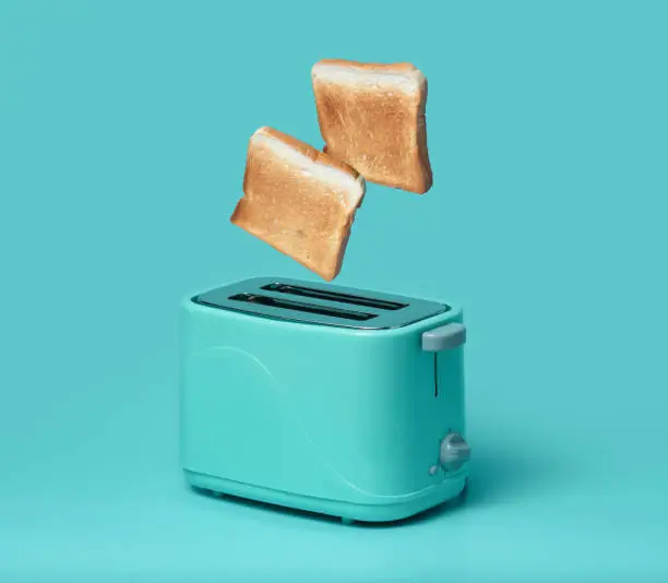 Photo of Bread popping up of toaster on mint green background