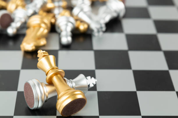 Golden and Silver chess surrounded by a number of fallen chess pieces, business strategy, chess battle, victory, success, teamwork concept. Chess on a chessboard. Chess board game, business ideas and competition. ajedrez de oro y plata rodeado de una serie de piezas de ajedrez caídas, estrategia de negocios, batalla de ajedrez, victoria, éxito, concepto de trabajo en equipo. ajedrez en un tablero de ajedrez. juego de mesa de ajedrez, ideas de negocio y competenci