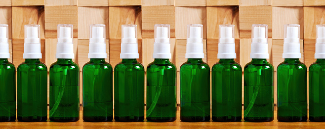 Set of cosmetics bottles with a body care liquid spray on the wooden tiled table. Natural herbal cosmetics and traditional medicine