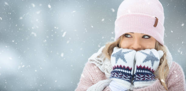 istock Girl warming her hands in gloves by breathing warm air on them. 1289130637