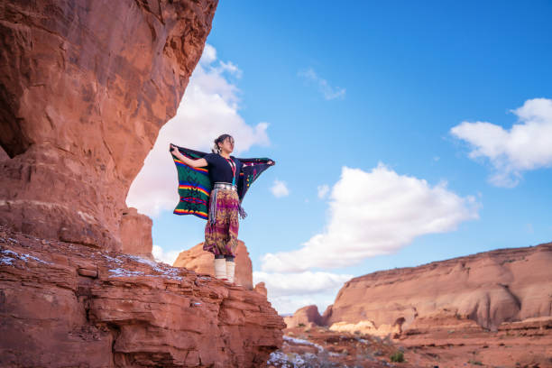 navajo frau öffnen ihre arme in einer mystischen pose, während sie sich im monument valley stammespark umschaut - navajo american culture indigenous culture women stock-fotos und bilder