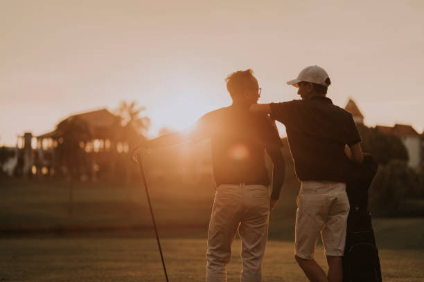 asian chinese father and son golfers looking at each other at golf course during sunset golf country club stock pictures, royalty-free photos & images
