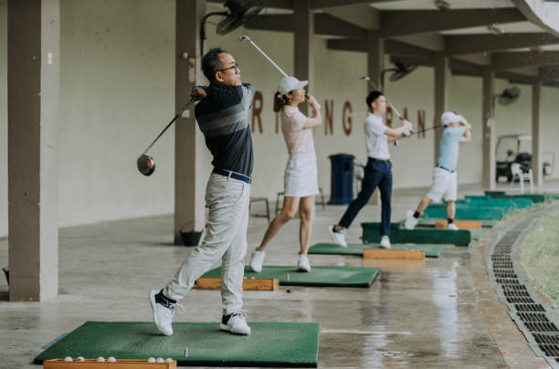 groupe de golfeurs chinois asiatiques balançant leur club de golf au terrain de golf de gamme de conduite - freedom tire swing tire swing photos et images de collection