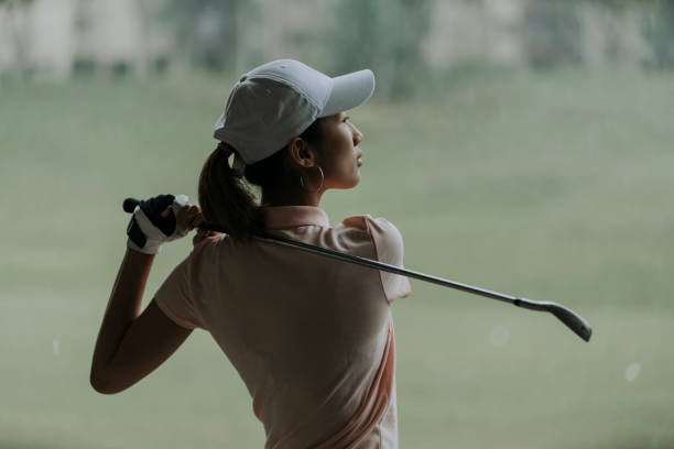 zuversichtlich asiatische chinesische reife frau golfer swinging golfclub auf golfplatz - playing golf fotos stock-fotos und bilder