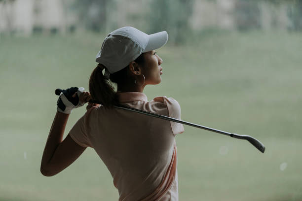 confiado asiático chino madura mujer golfista balanceo club de golf en el campo de golf - golf power golf course challenge fotografías e imágenes de stock