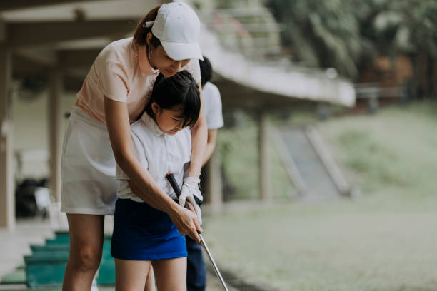 asiática chinesa madura golfista ensinando jovem estudante jogando golfe em campo de golfe de alcance de condução - golf women female concentration - fotografias e filmes do acervo