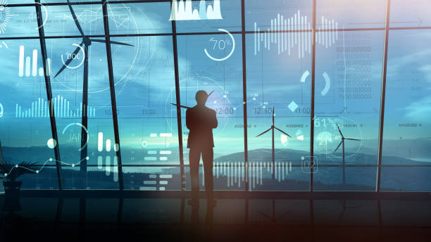 istock In a dark office, a man looks at big data by the window overlooking a wind farm. 1289140673