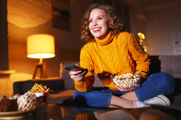 istock Happy woman with popcorn watching TV at night 1289140701
