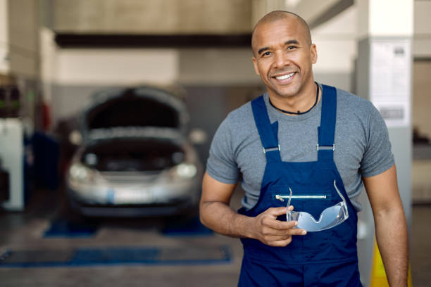 porträt des glücklichen afroamerikanischen automechanikers in einer werkstatt. - kleinunternehmen stock-fotos und bilder