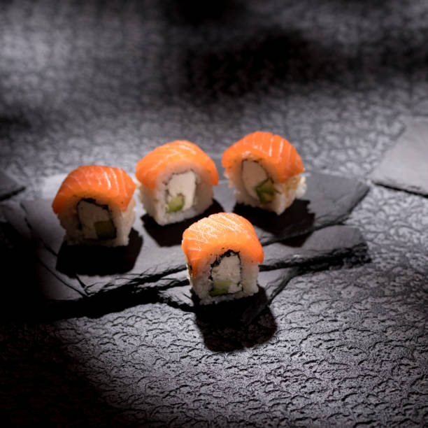 istock Appetizing rolls on a textured black background. Japanese food concept. Close-up. Copy space. Square. 1289140826