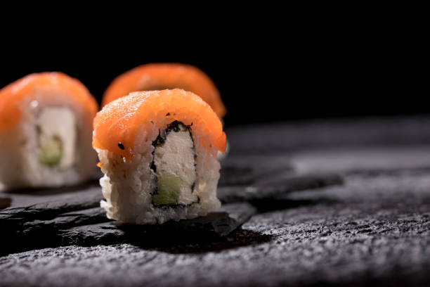istock Appetizing rolls on a textured black background. Japanese food concept. Close-up. Copy space. 1289140898