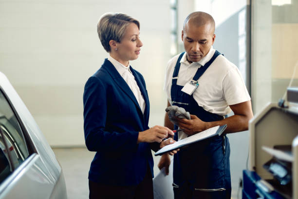 istock Businesswoman and auto mechanic analyzing paperwork in a workshop. 1289141108